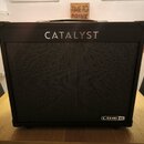Černý kytarový kombo zesilovač s látkovou mřížkou. V horní části je bílý nápis CATALYST a v pravém dolním rohu logo LINE 6. Povrch je v dobrém stavu…