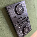 Černý DJ 컨트롤러 s dvěma jogovými koly a centrálním mixážním sekcí. Na přístroji jsou viditelné nápisy rekordbox, Pioneer DJ a model DDJ-400. Povrch je…