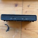 Černý obdélníkový přístroj z plastu s přepínači na zadní straně. Jsou zde viditelné nápisy: 3+4 MONO, B STEREO, 1+2 MONO a A STEREO. Povrch je matný…