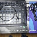 Černý sekvenční syntezátor Novation Circuit v originálním plastovém obalu, položený na krabici s nápisem „The inspirational grid-based groove box“. N…