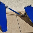 Modré pedály k bicím sadě s kovovými mechanismy. Nástroje jsou v modré barvě, povrch je matný a vykazuje mírné známky opotřebení. Na fotce nejsou žád…