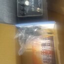 Kytarový efekt v černé barvě s nápisy ehx tartan a electro-harmonix. Na pedálu jsou čtyři ovládací knoflíky, jeden bílý a tři černé. Vedle efektu je…