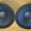 Dva černé reproduktory s kulatým tvarem a centrálním kalotkou. Jsou umístěny vedle sebe na dřevěném povrchu. Na reproduktorech nejsou viditelné žádné…