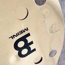 Detail zlatavého kovového činchimu s několika otvory. Na povrchu je černý nápis MEINL a stylizované logo ve tvaru čísla 8. V pravé části je vyražen t…