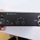 Zadní strana audio rozhraní s kovovým stříbrným horním panelem a černým spodním panelem, waarvaného šasi je zakončeno dřevěnými bočními panely. Na ho…