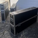 Tři černé transportní bedny s kovovými hranami a rohy. Bedny mají kovové zámky a úchytky, povrch je černoý s viditelným opotřebením a škrábancami. Na…
