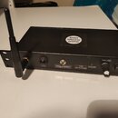 Černý kovový bezdrátový přijímač s anténou. Na horní straně je bílá nálepka s nápisem ROCKY WIRELESS SYSTEM. Přední panel obsahuje ovrtěvník, přepína…