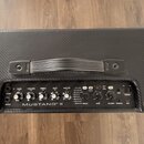 Horní pohled na černý kytarový kombo zesilovač s texturovaným povrchem a úchytkou. Na ovládacím panelu jsou nápisy GAIN, VOLUME, TREBLE, BASS, MASTER…