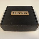 Černá papírová krabička s hnědým obdélníkovým polem, ve kterém je černý nápis FRIEDMAN. Na spodní hraně krabice je uveden web FRIEDMANAMPLIFICATION.C…