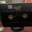 Zadní strana černého kytarového komba s nápisem MODEL Frontman 212R™. Jsou zde viditelné dva reproduktory s logem Fender a nápisem MUSICAL INSTRUMENT…