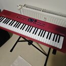Červený digitální klavír značky Roland, model GO:KEYS 3. Nástroj je umístěn na černém skládacím stojanu. Povrch je v dobrém stavu bez viditelného opo…