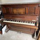 Hnědé dřevěné piano s klaviaturou. Na přední straně nad klávesami je nápis "Koch & Zorn". Vpravo u kláves se nachází malý štítek s nečitelným textem.…