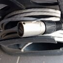 Šedý kabel namotaný na černém plastovém držáku. Na konci kabelu je kovový konektor s černým plastovým krytem, na kterém je částečně viditelný nápis N…