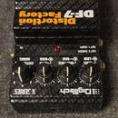 Kytarový efekt pedál značky DigiTech, model Distortion Factory DF-7. Zařízení má černý povrch s karbonovým vzorem a čtyři ovládací knoflíky s popisky…