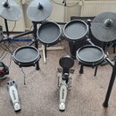 Elektronická bicí souprava s černými pady a činely. Na modulu, činelech a pedálech je viditelné logo ALESIS; na modulu je dále nápis NITRO. Souprava…