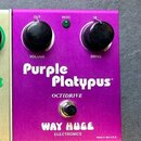 Fialový kytarový efekt s nápisy Purple Platypus™, OCTIDRIVE a WAY HUGE ELECTRONICS. Na horní straně jsou dva černé otočné knoflíky s popisky VOLUME a…