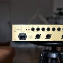 Zadní strana zlatého elektronického zařízení s nápisy Model WP-100 a CE. Jsou zde viditelné vstupy a výstupy typu jack, přepínače Ground Lift a volič…