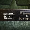 Zadní strana černého rackového zařízení značky dbx. Jsou zde vidět napájecí konektor, několik výstupů OUTPUT a vstupy INPUT s rozhraním XLR a jack. N…