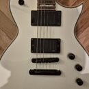 Bílá elektrická kytara s dvěma humbuckery a černým hardwarem. Na obou snímačích je viditelné logo emg. Kytara má tři černé ovládací knofíky a jeden p…