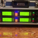 Dvě stříbrné bezdrátové přijímače značky SHURE umístěné v racku pod modrým kufrem s nápisem WISENT. Obě jednotky mají zelené LCD displeje, LED indiká…