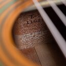 Detailní pohled do vnitřku akustické kytary na dřevěný label. Na dřevě je černým tiskem uveden nápis L-5 a pod ním číslo 1102. Povrch dřeva vykazuje…