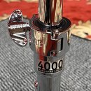 Detail chromovaného kovového stojanu s utahovacím knoflíkem. Na těle je vyryt nápis NODE a níže se nachází štítek s textem 4000 HARDWARE SERIES a dro…