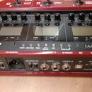Červený multifunkční efektový procesor s nápisy ZOOM a G3. Zařízení má tři displeje, devět ovládacích knoflíků a řadu konektorů na zadní straně, včet…