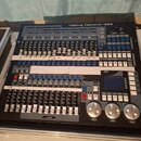 Černý svítlóvkový kontrolér s nápisem Lighting Controller 1024. Zařízení obsahuje množství tlačítek, posuvníků a tři velké stříbrné otočné ovladače v…