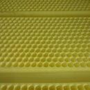 Detailní záběr na žlutý pěnový materiál s pravidelnou strukturou malých kulatých otvorů. Povrch je hladký a bez viditelných značek či nápisů.