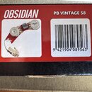 Fotografie krabičky s červeným a černým potiskem. Na povrchu je bílý nápis OBSIDIAN a PB VINTAGE 58, dále čárcový kód s číslem 9 421904 089563. Vlevo…