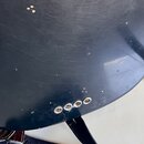 Detail tmavě modré lakované plochy hudebního nástroje s viditelnými drobnými škrábancemi a odpáleninami. V dolní části jsou čtyři kovové kolíčky pro…