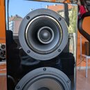 Černý reproduktor s lesklým povrchem. Na horním jednotce je nápis Cabasse a pod ní text SOURCE A COHERENCE SPATIALE. Pod horním reproduktorem se nach…