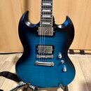 Modrá elektrická kytara s výraznou masivní strukturou dřeva a tmavými okraji. Nástroj má dva humbuckery s kovovými kryty, tři ovládací knoflíky a Tun…