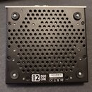 Spodní strana černého elektronického zařízení s perforovaným kovovým krytem. V dolní části je bílá nálepka s logem UAD 2 DUO CORE, čárovým kódem a čí…