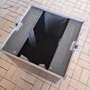 Fotografie zobrazuje otevřený, prázdný transportní kufr s kovovými hranami a vrchními zámky. Vnitřek je vyložen tmavým, pravděpodobně pěnovým nebo te…