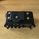 Černý digitální nahrávací zařízení s montážním závitem na horní straně. Na přední části je viditelné logo TASCAM, čtyři otočné oválné knoflíky a ovlá…