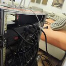 Černý rackový case s kovovými hranami a hliníkovým profilem, v němž jsou osazena elektronická zařízení. Na zadní straně jsou zapojeny černé kabely do…