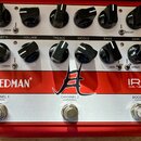 Červený kytarový předzesilovač s bílým horním panelem. Na červeném spodním panelu jsou nápisy Friedman, IR-J DUAL TUBE PREAMP a logo ve tvaru stylizo…