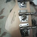 Zadní strana světlé dřevěné hlavy kytary se třemi chromovanými ladičkami. Na dřevě je černý nápis Crafted in China a s/n CY130905421. Povrch dřeva i…