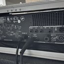 Zadní strana černého zesilovače s ovládacími prvky a technickými nápisy. Jsou zde vidět vstupy a výstupy označené jako PATCH BAY (FOOTSWITCH, TUNER,…