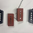 Čtyři komponenty elektrokitary: dva snímače s červeným povrchem a dvě černé plastové kryty. Snímače mají čtyři viditelné kovové póly v řadě, povrch j…