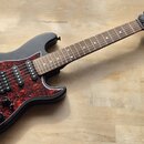 Elektrická kytara s matně černým tělem a červeně mramorovaným pickguardem. Na hlavě hnedu kytary je bílý nápis Harley Benton a Standard Series. Nástr…