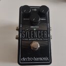 Černý kytarový efekt s nápisy THE SILENCER a noise gate/effects loop. Na horní straně jsou tři černé ovládací knoflíky s popisky RELEASE, REDUCTION a…