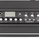 Černý kytarový zesilovač s texturovaným povrchem. Na ovládacím panelu jsou nápisy INPUT, GAIN, TREBLE, MID, BASS, VOLUME MASTER a TUNER, dále LIVE/PR…