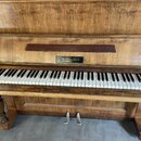 Dřevěný piano s výraznou masivní strukturou a viditelným opotřebením povrchu. Na přihradce nad klávesami je nápis M. Muchan BRNO. Klávesnice vykazuje…