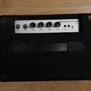 Černý basový kombo zesilovač s povrchem z látky a ovládacím panelem v bílé barvě. Na panelu jsou nápisy ZAMVIC AMPLIFIER a BC10, pět regulačních knof…
