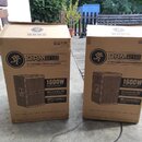 Dvě hnědé kartonové krabice s nápisem DRM212 12" PROFESSIONAL POWERED LOUDSPEAKER. Na krabicích je vidět logo s běžícím postavou, text 1600W, Advance…