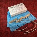 Tři humbuckery s kovovými kryty a bílo-černým zapojeními kabelů, položené na modrém ochranném papíře. Na krytech je vyražen nápis TOMA pickups. Součá…