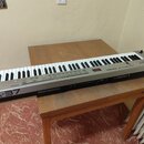 Stříbrný klaviatura s 37 klávesy položená na dřevěném stole. Na levé straně je nápis A-37 a v pravém horním rohu logo Roland. Na ovládacím panelu jso…