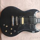 Černá elektrická kytara s dvojstupňovými humbuckery, z nichž je jeden v krčkové pozici zlatý. Na těle jsou čtyři zlaté ovládací knofíky a přepínač tó…
